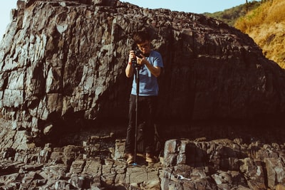人拿着相机,站在悬崖白天

